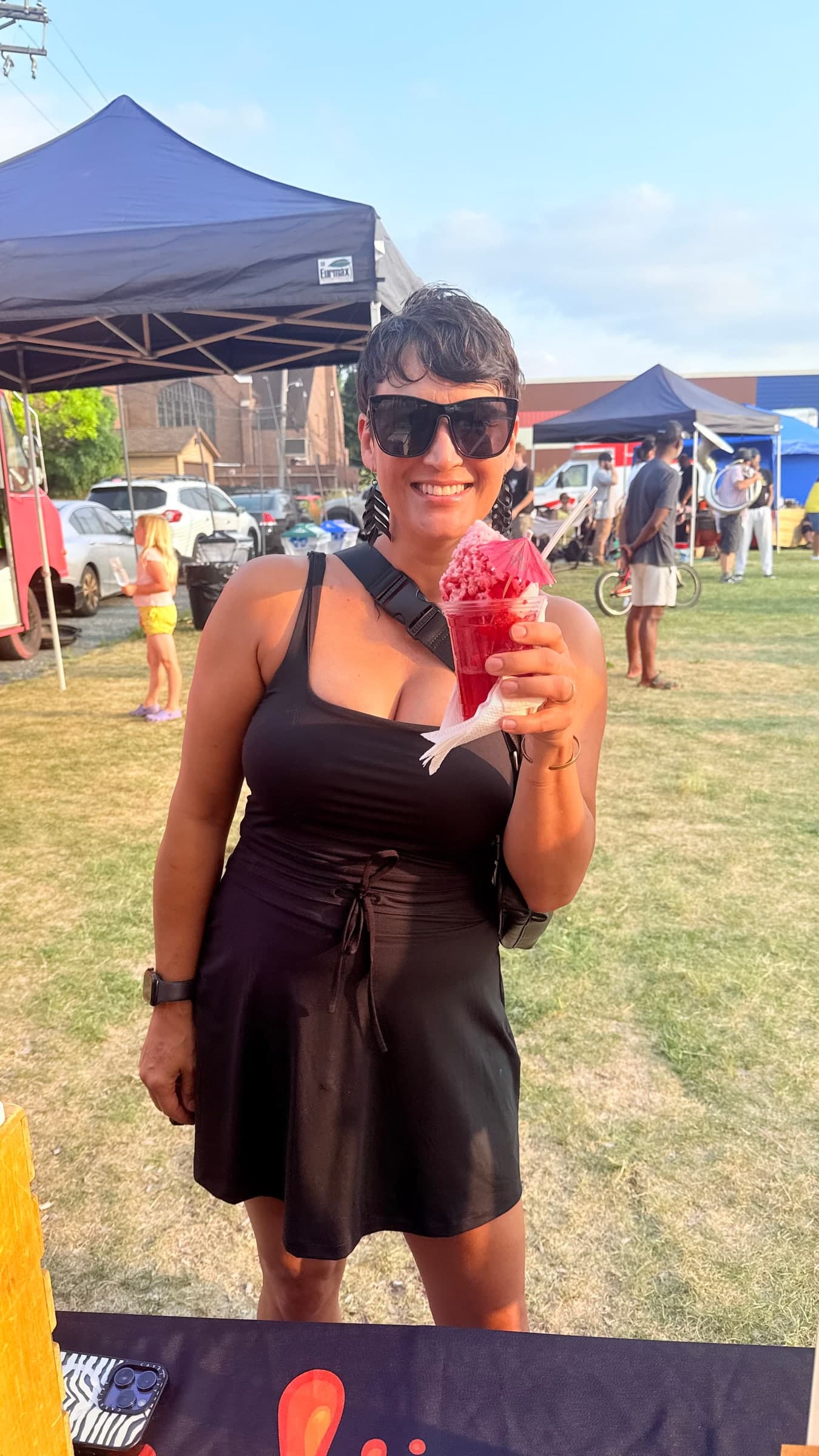 A guest holding a red sno ball with a cocktail umbrella at an outdoor event