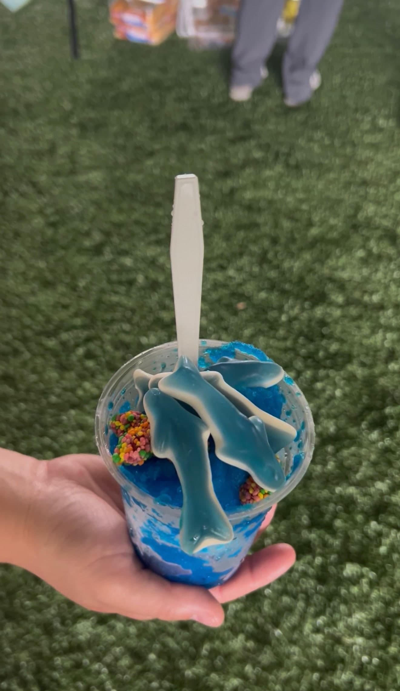A blue sno ball topped with gummy sharks and Nerds
